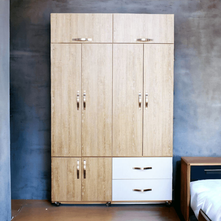 La imagen muestra un closet de madera con un acabado en color madera clara. El armario tiene varias secciones: en la parte superior, dos puertas pequeñas; en la parte media, cuatro puertas grandes; y en la parte inferior, dos puertas pequeñas a la izquierda y dos cajones grandes en color blanco a la derecha. Todas las puertas y cajones tienen manijas metálicas plateadas. El armario está montado sobre ruedas para facilitar su movilidad.