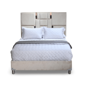 La imagen muestra una cama con un diseño moderno y sofisticado. La cama tiene un cabecero alto tapizado en tela color beige, con un patrón geométrico de paneles acolchados que le da un toque de elegancia y estilo. La base de la cama también está tapizada en el mismo material y color que el cabecero. Las patas de la cama son de metal, proporcionando un soporte robusto y un aspecto contemporáneo. El colchón es de color blanco con una funda acolchada que presenta un patrón de costura en forma de ondas.