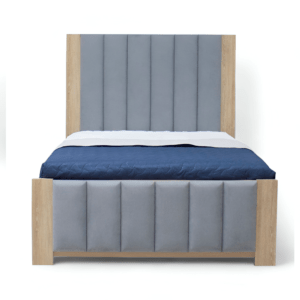 La imagen muestra una cama con un diseño moderno y minimalista. El cabecero y el piecero están tapizados en tela gris con paneles verticales acolchados. Los bordes del cabecero y el piecero están hechos de madera clara, proporcionando un contraste elegante con la tela gris. La cama está vestida con un edredón azul oscuro y una sábana blanca visible en la parte superior.