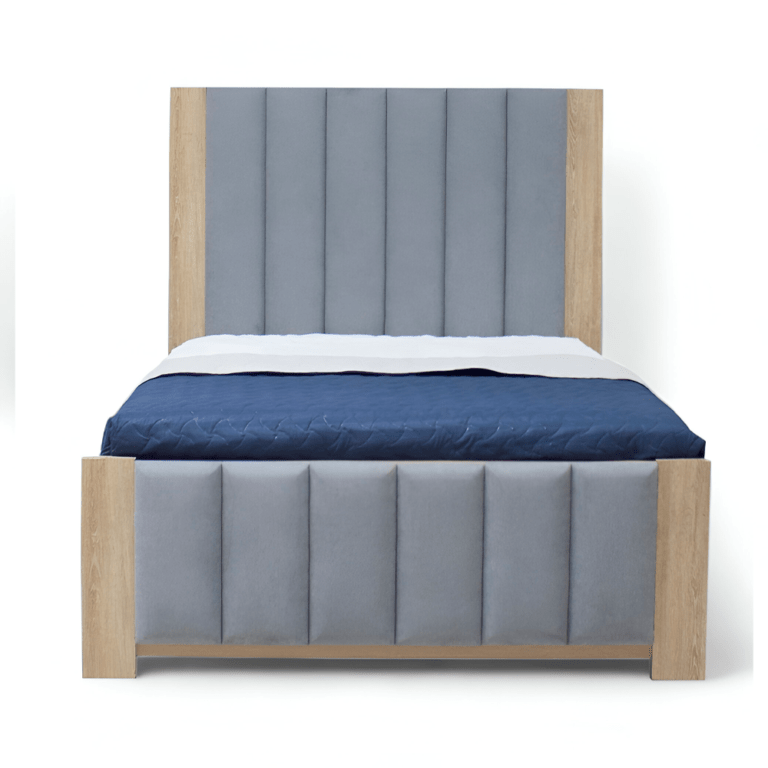 La imagen muestra una cama con un diseño moderno y minimalista. El cabecero y el piecero están tapizados en tela gris con paneles verticales acolchados. Los bordes del cabecero y el piecero están hechos de madera clara, proporcionando un contraste elegante con la tela gris. La cama está vestida con un edredón azul oscuro y una sábana blanca visible en la parte superior.