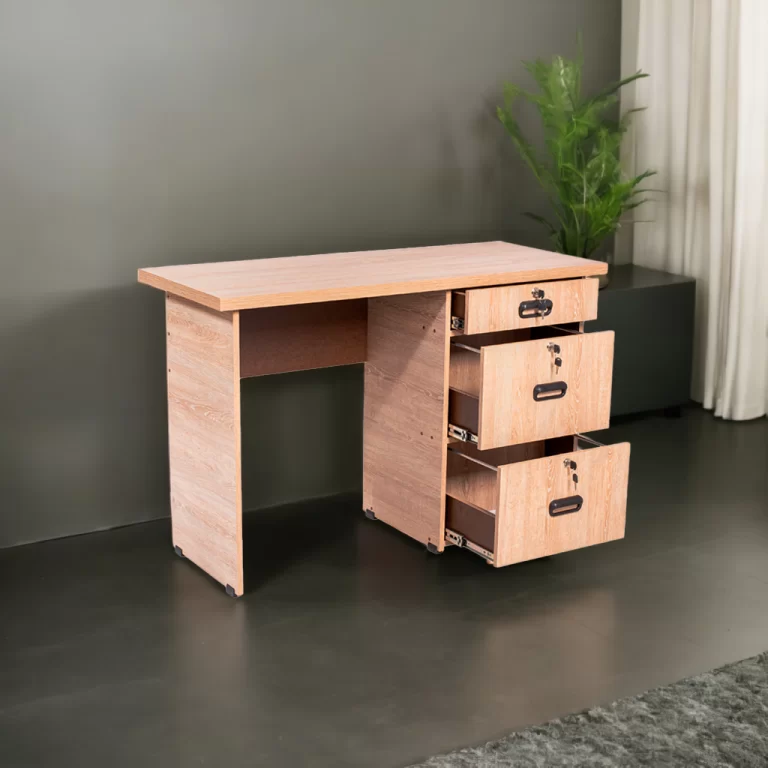 La imagen muestra un escritorio compacto de color madera clara, ideal para oficinas pequeñas o espacios de trabajo en casa. El escritorio tiene una superficie de trabajo rectangular y una base sólida. A la derecha, hay una unidad de almacenamiento con tres cajones que se extienden hacia fuera, todos con manijas negras y cerraduras integradas.